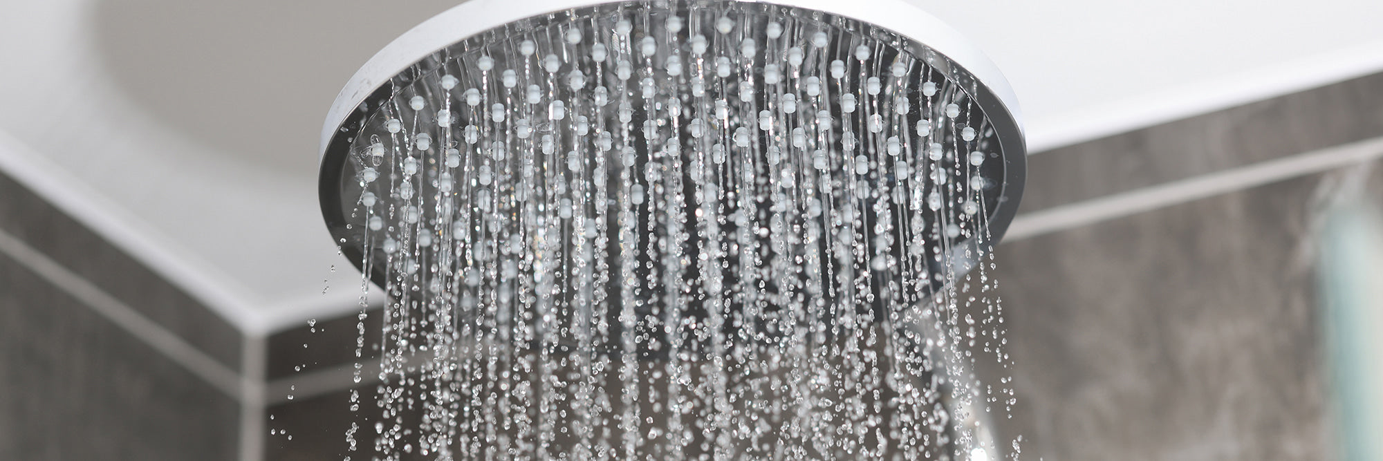 Close-up of a shower head with water droplets in a bathroom setting
