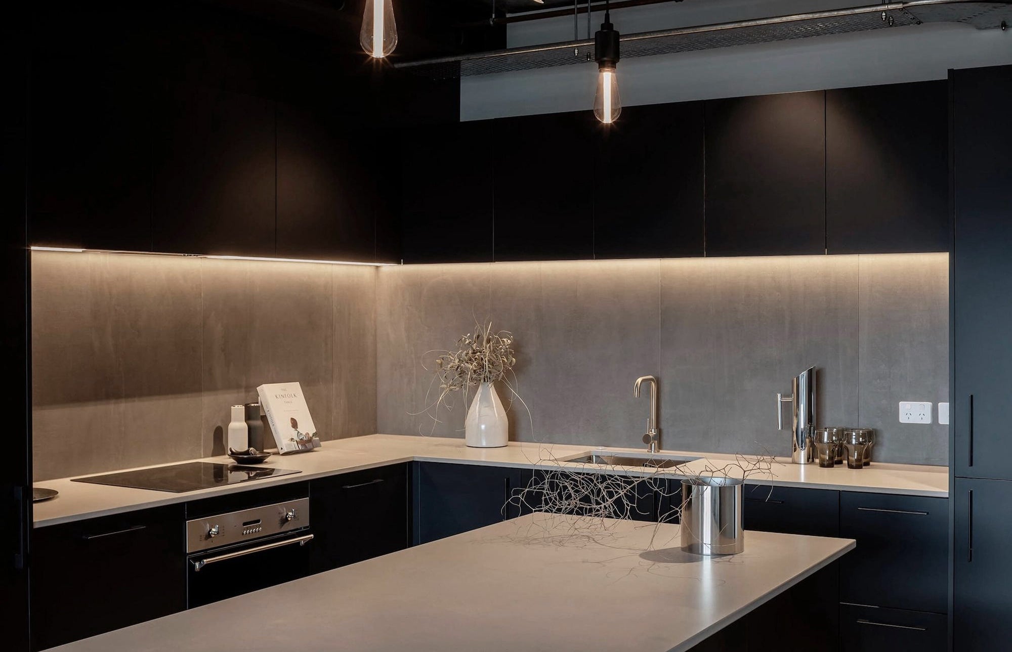 Modern kitchen with dark cabinets, gray countertops, and a backsplash.