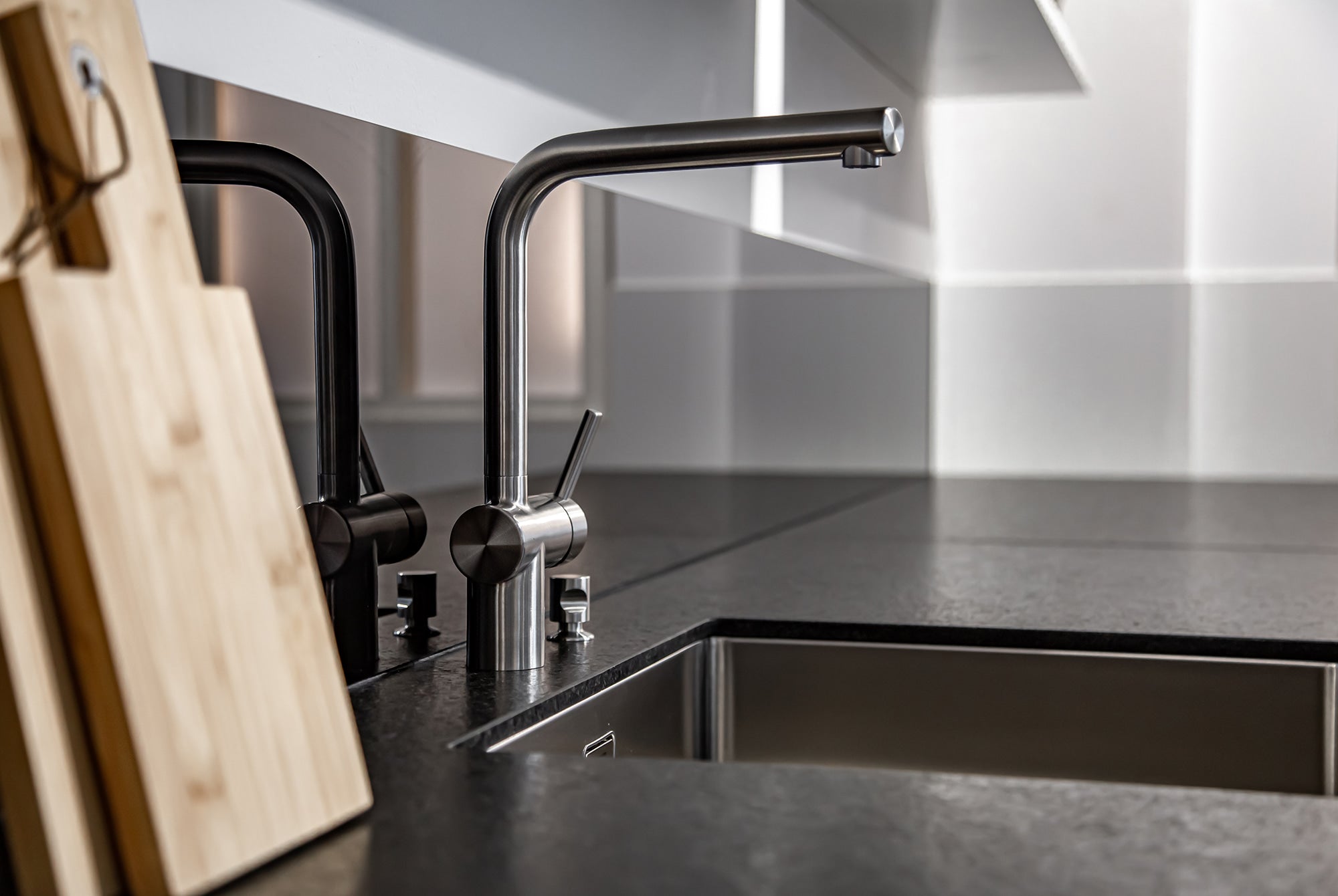 Modern kitchen faucet with black and silver design on a dark countertop.