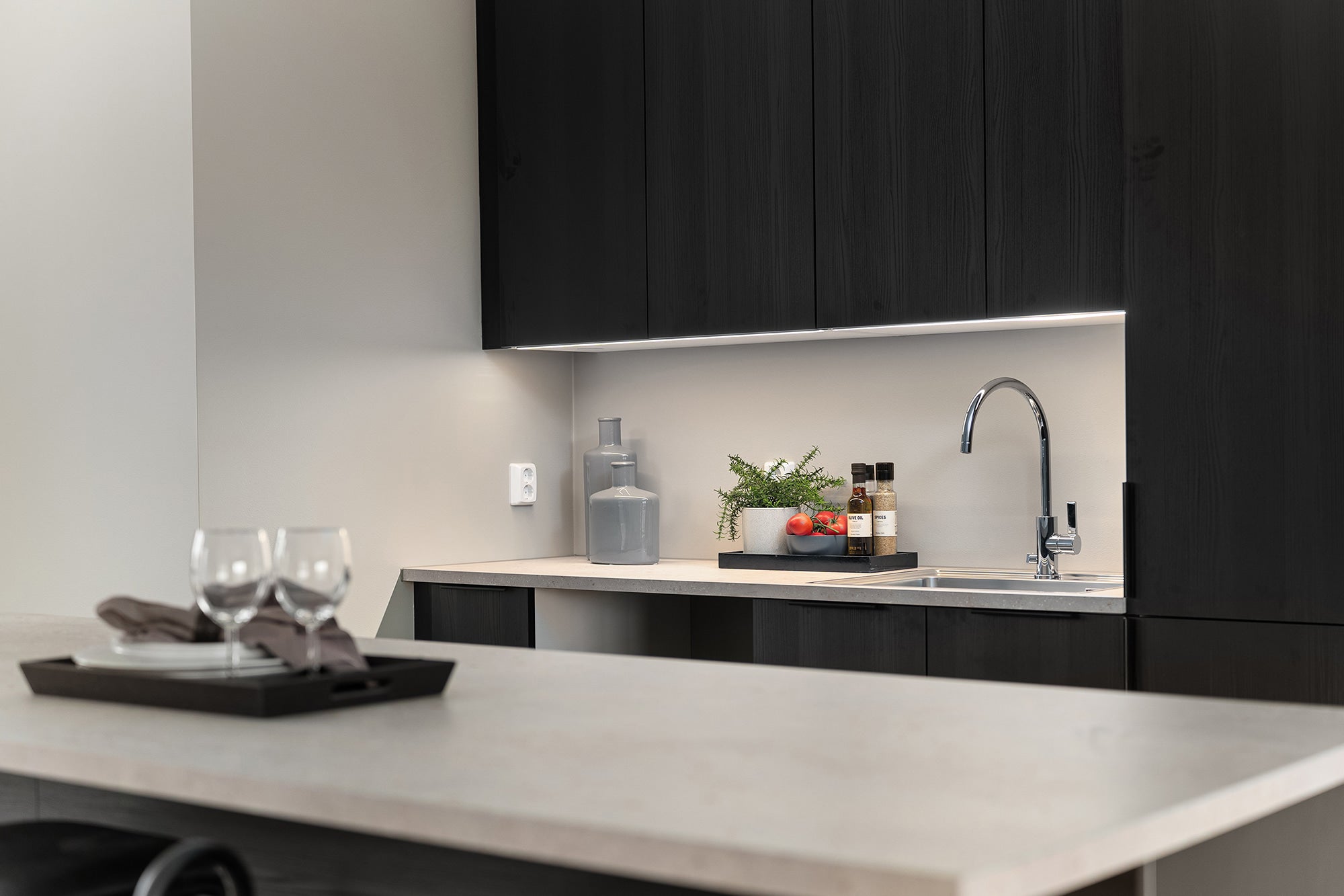 Modern kitchen with black cabinets, white countertop, and sink area.