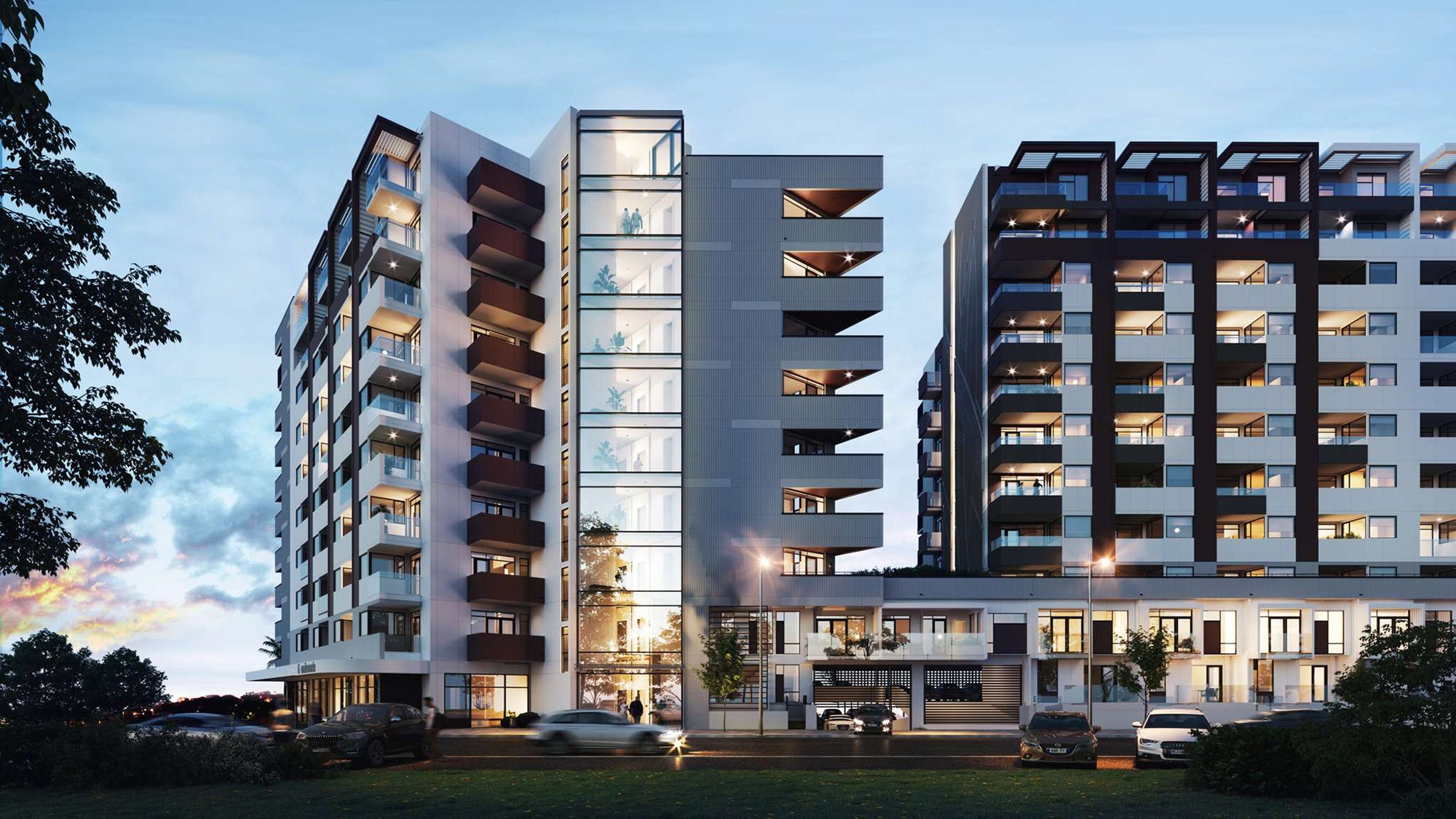 Modern apartment buildings with balconies and cars parked in front, set against a blue sky.